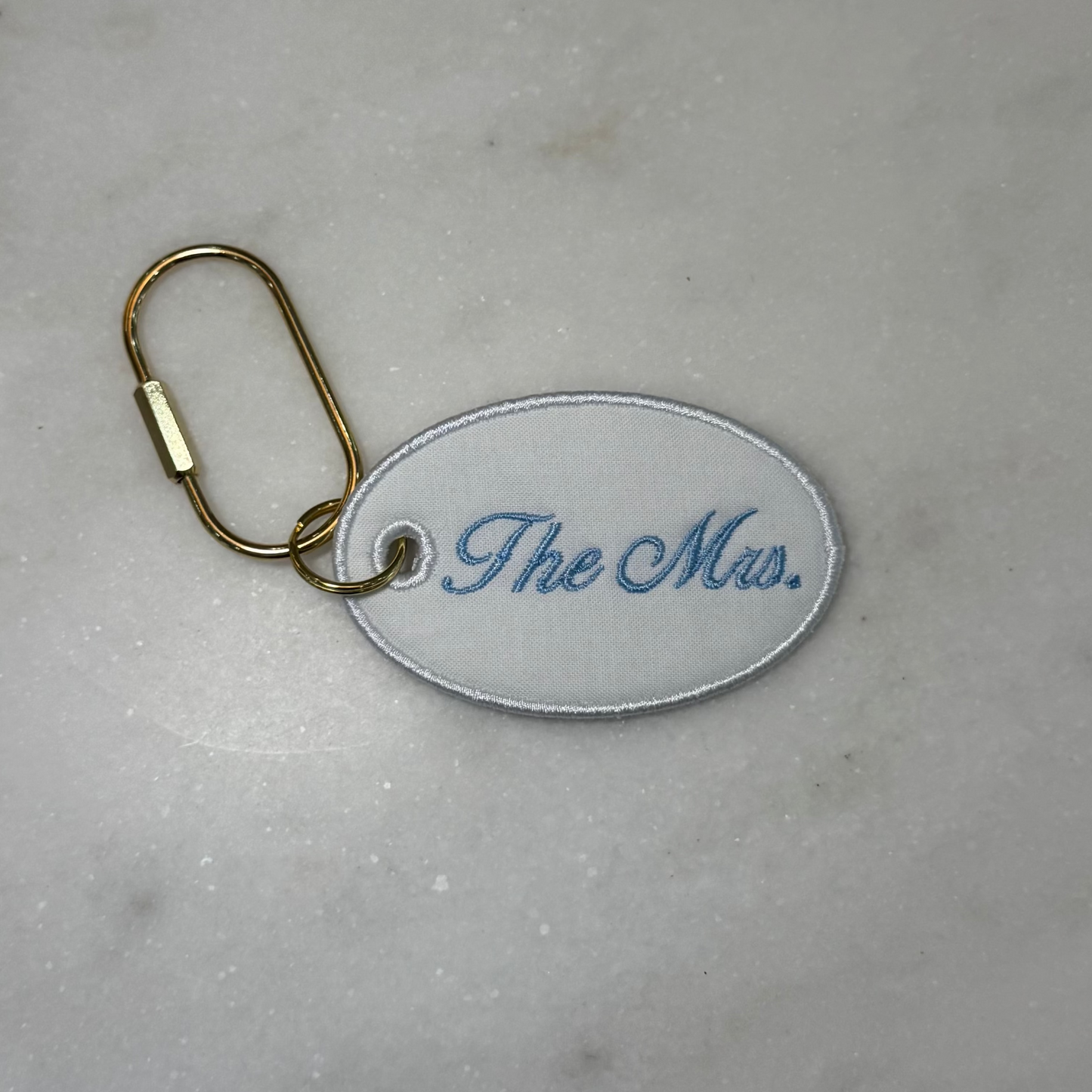 Keychain with 'The Mrs.' text on a marble surface