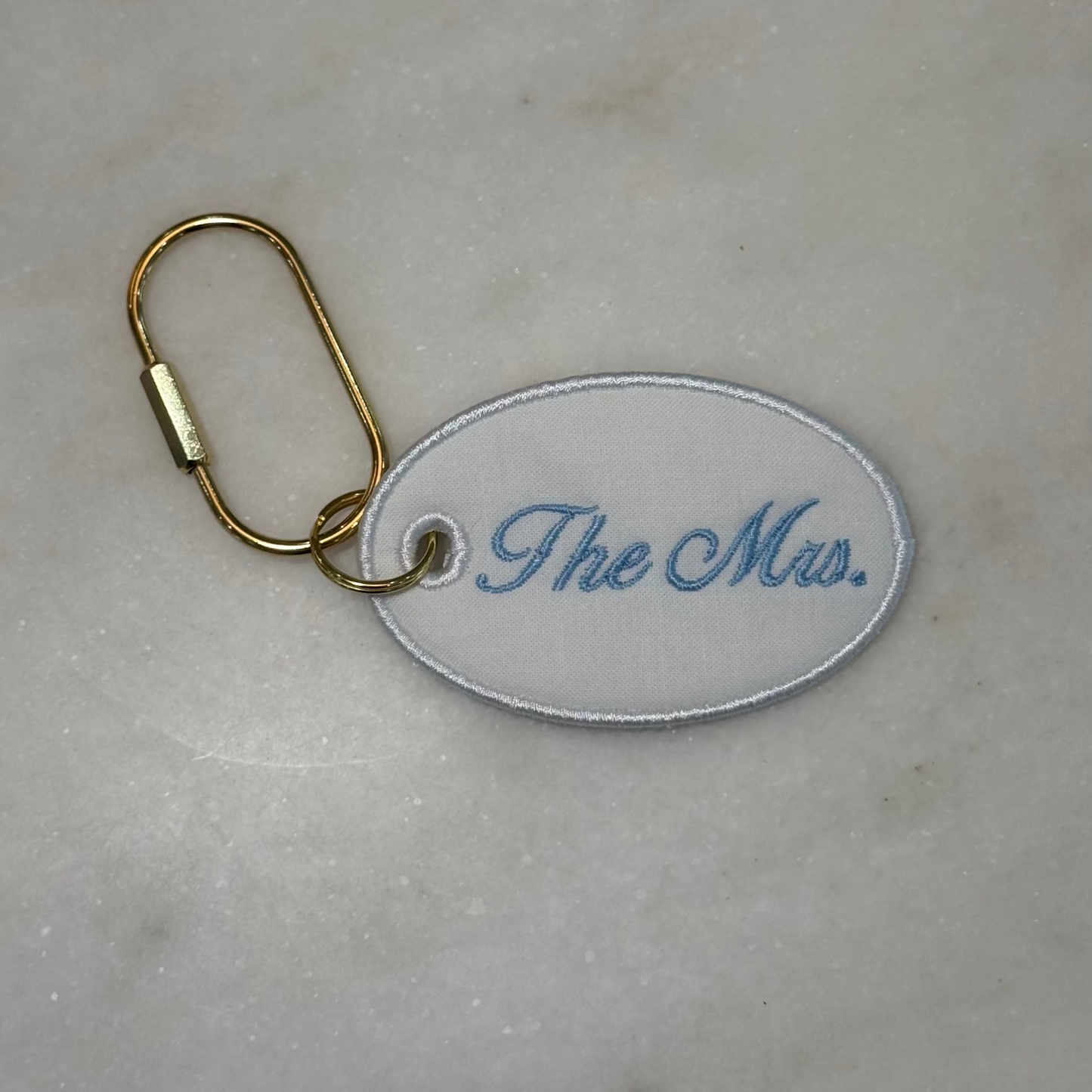Keychain with 'The Mrs.' text on a marble surface