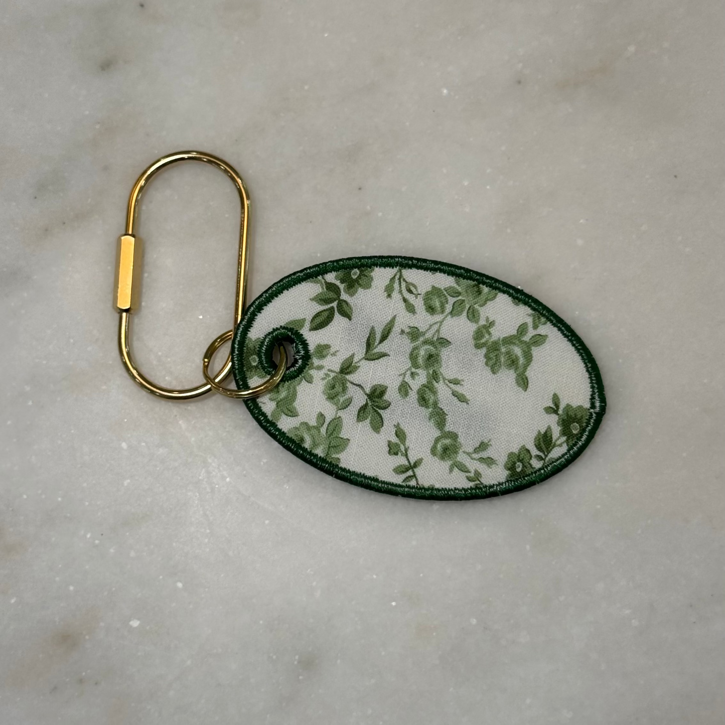 Keychain with green floral pattern on a beige surface