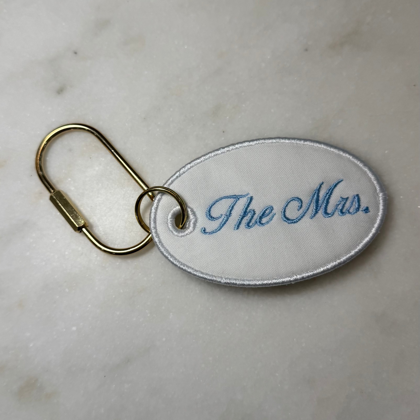 Keychain with 'The Mrs.' text on a marble surface
